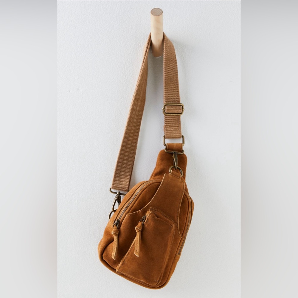Sling style, suede, adjustable woven strap, outer pocket. Washed whisky color.